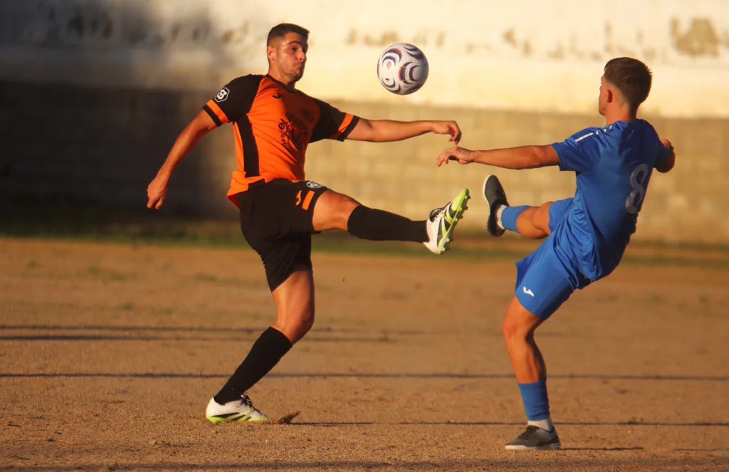 Un jugador del Quatretonda CF y otro del CD Albaidense pelean un balón alto en el campo de tierra de Quatretonda