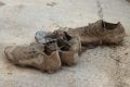 Botas de fútbol cubiertas de barro tras la dana de 2024 en un campo de l’Horta Sud
