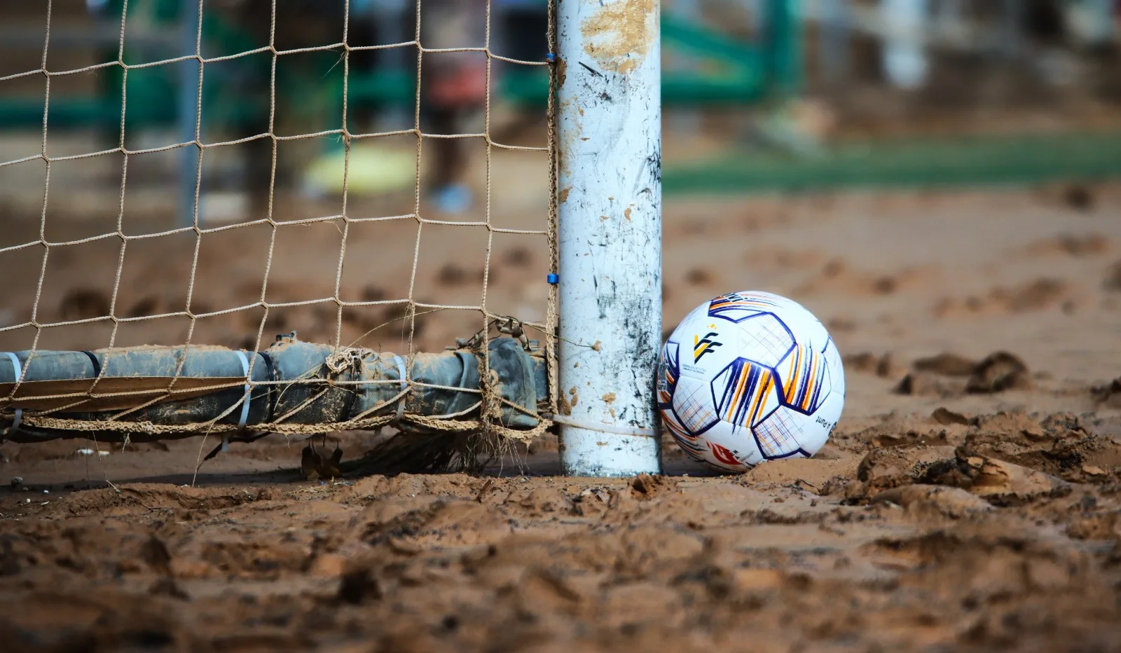 Pilota de futbol al costat del pal d’una porteria enfonsada en el fang de la dana