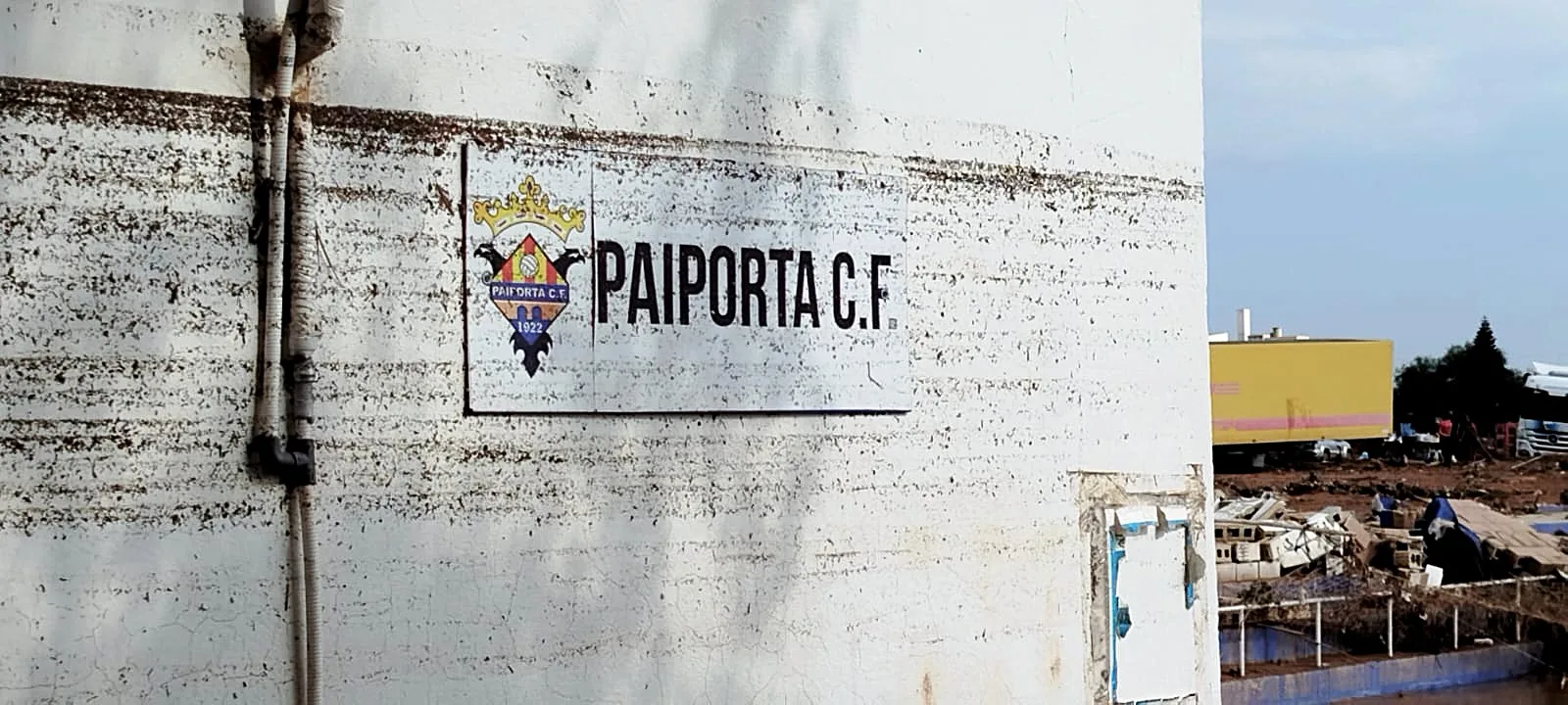 Placa del Paiporta CF en un mur tacat de fang després de la dana