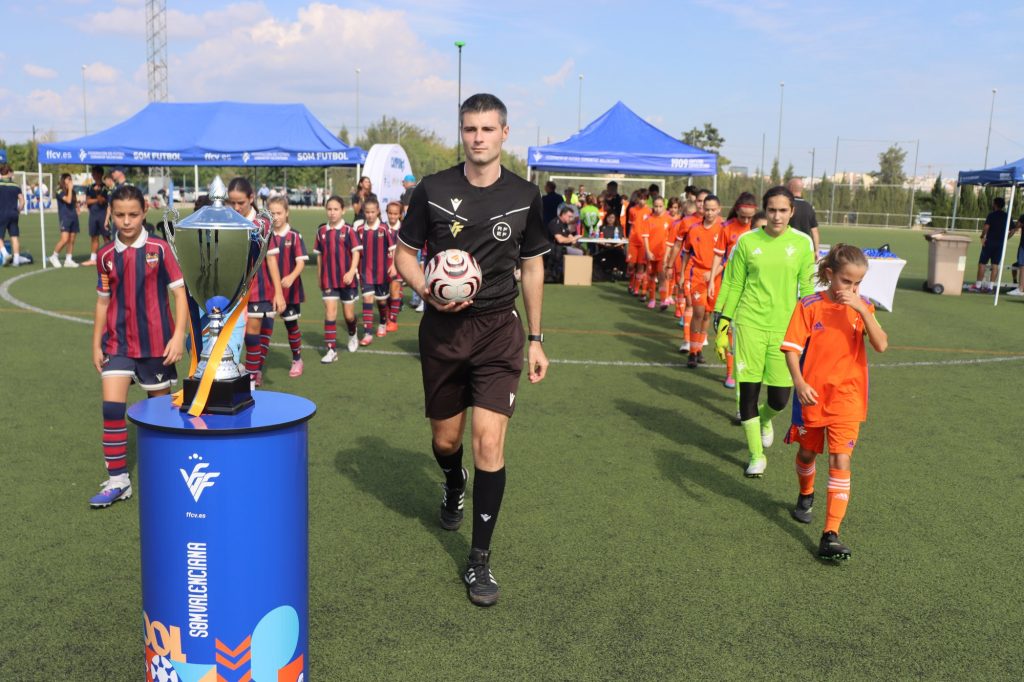 Els equips eixen al camp al costat del trofeu en el II Torneig Tornem! de futbol aleví a Manises